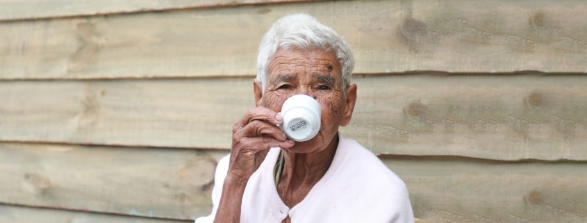 An elderly man sitting and drinking coffee