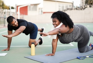 A woman and her personal trainer stretching outside