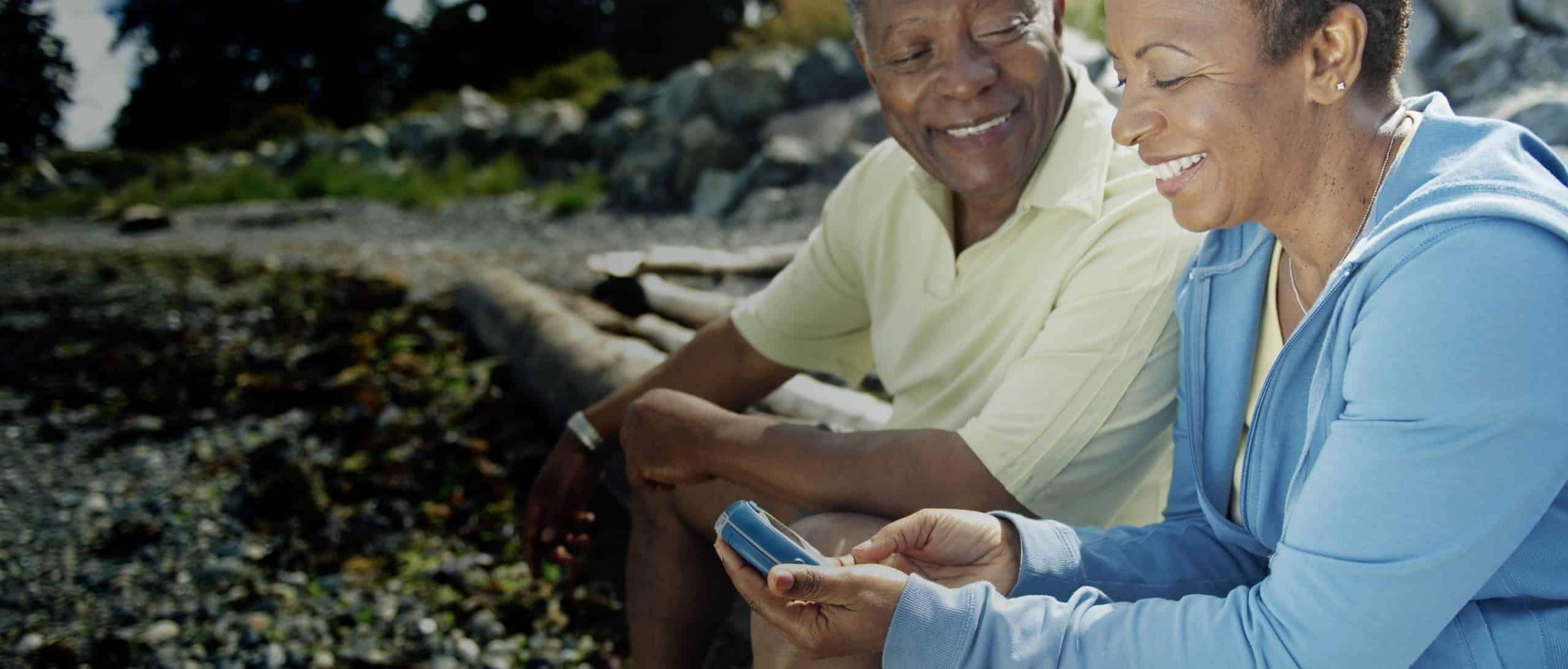 A couple sitting outside, looking at a glucose meter