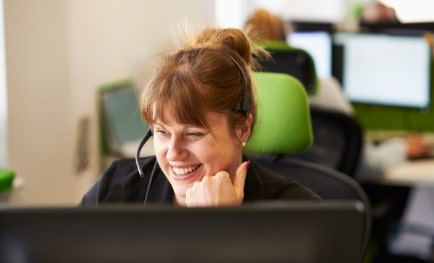 A customer support woman on the phone in her cubicle at an office