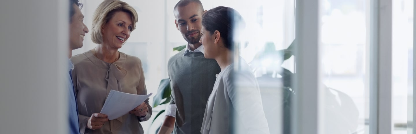 A group of insurance professionals standing and talking in a conference room