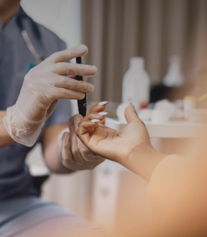 A closeup of a medical professional using a lancet device on a female patient's finger