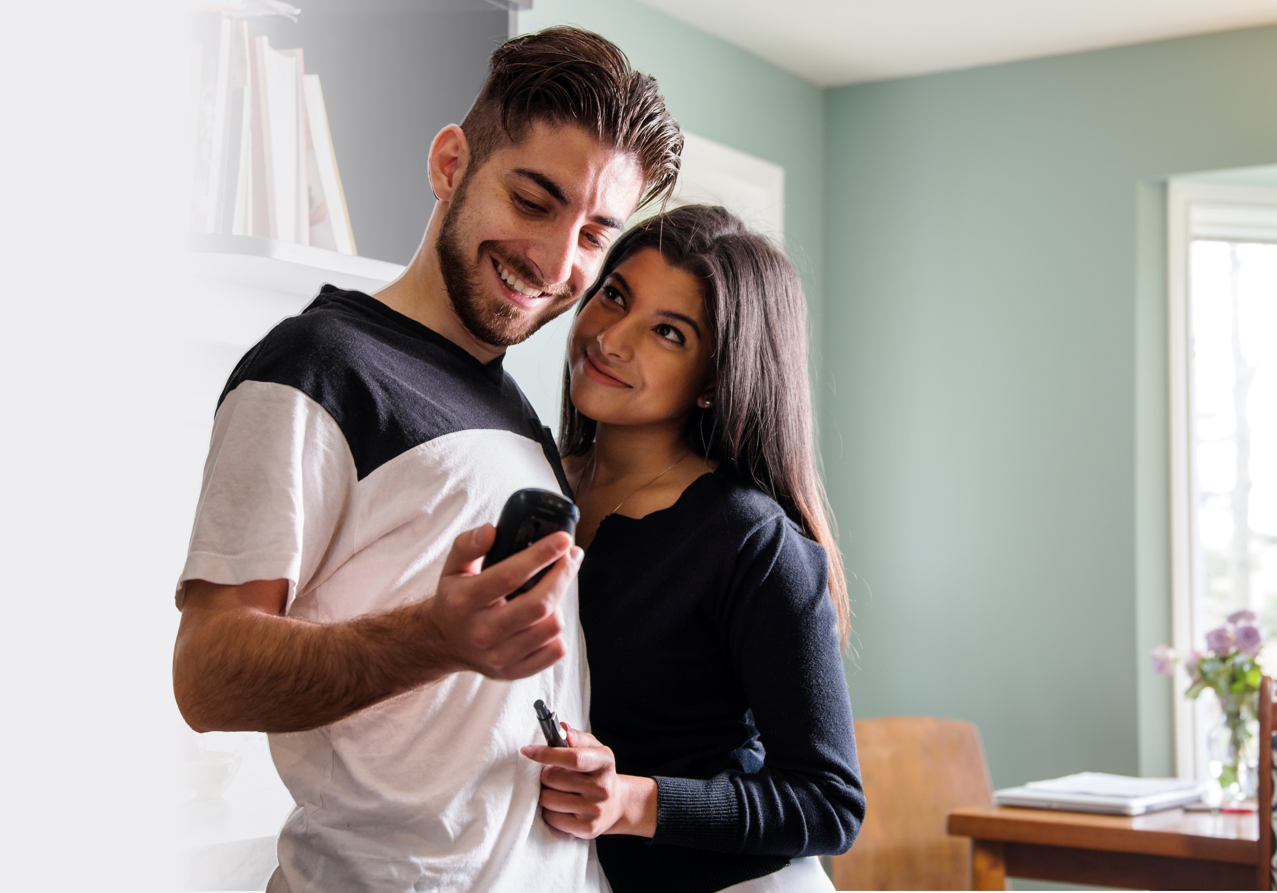 A couple hugging while they look at a glucose meter