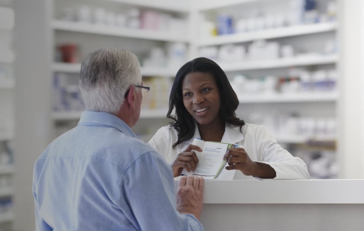 Female pharmacist showing a male customer a brochure