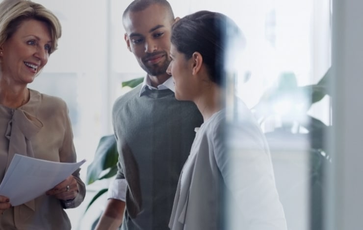 A group of insurance professionals standing and talking in a conference room