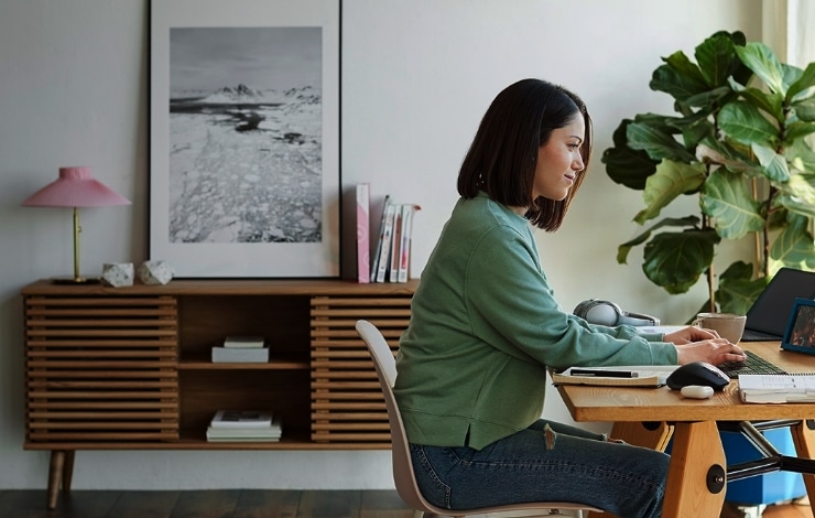 A woman sitting at her desk in front of a window, looking at her computer