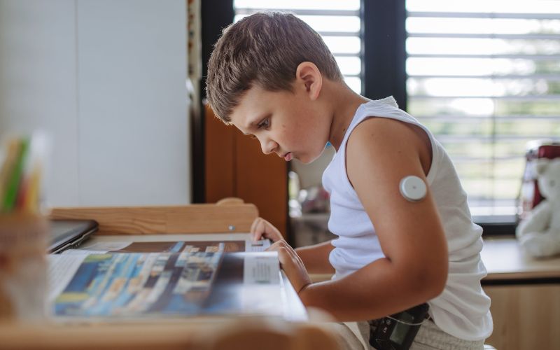 A diabetic boy is shown doing homework while wearing a closed loop insulin pump system.