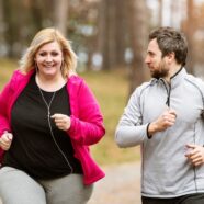 A smiling overweight diabetic woman jogs alongside a male friend. Practicing healthy habits for diabetes is key.