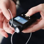 Closeup shot of a woman's hands holding a closed loop insulin pump.